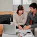 Jeune couple examinant des documents de crédit immobilier avec une calculatrice à la table de la cuisine.