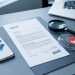 Bureau professionnel avec document bancaire vierge, smartphone, loupe, bouclier de protection et symbole d’alerte évoquant l’identification et la contestation d’un prélèvement non reconnu.