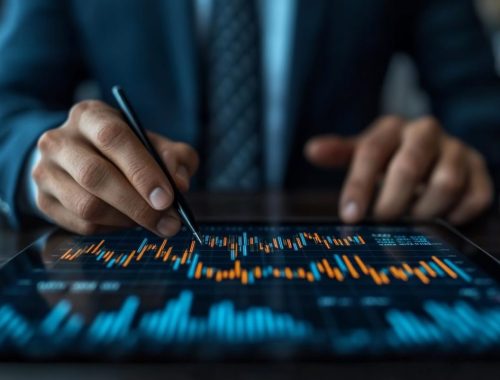 Dirigeant consultant un portefeuille d’investissement sur son ordinateur, avec des documents financiers posés sur le bureau.