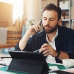 Entrepreneur en dropshipping examinant les bénéfices de sa boutique en ligne sur un ordinateur et un carnet de notes.