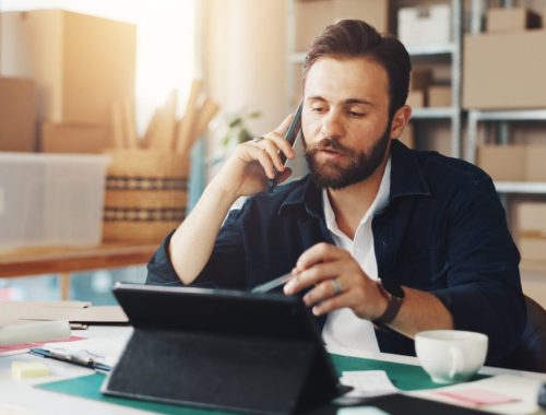 Entrepreneur en dropshipping examinant les bénéfices de sa boutique en ligne sur un ordinateur et un carnet de notes.