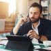 Entrepreneur en dropshipping examinant les bénéfices de sa boutique en ligne sur un ordinateur et un carnet de notes.